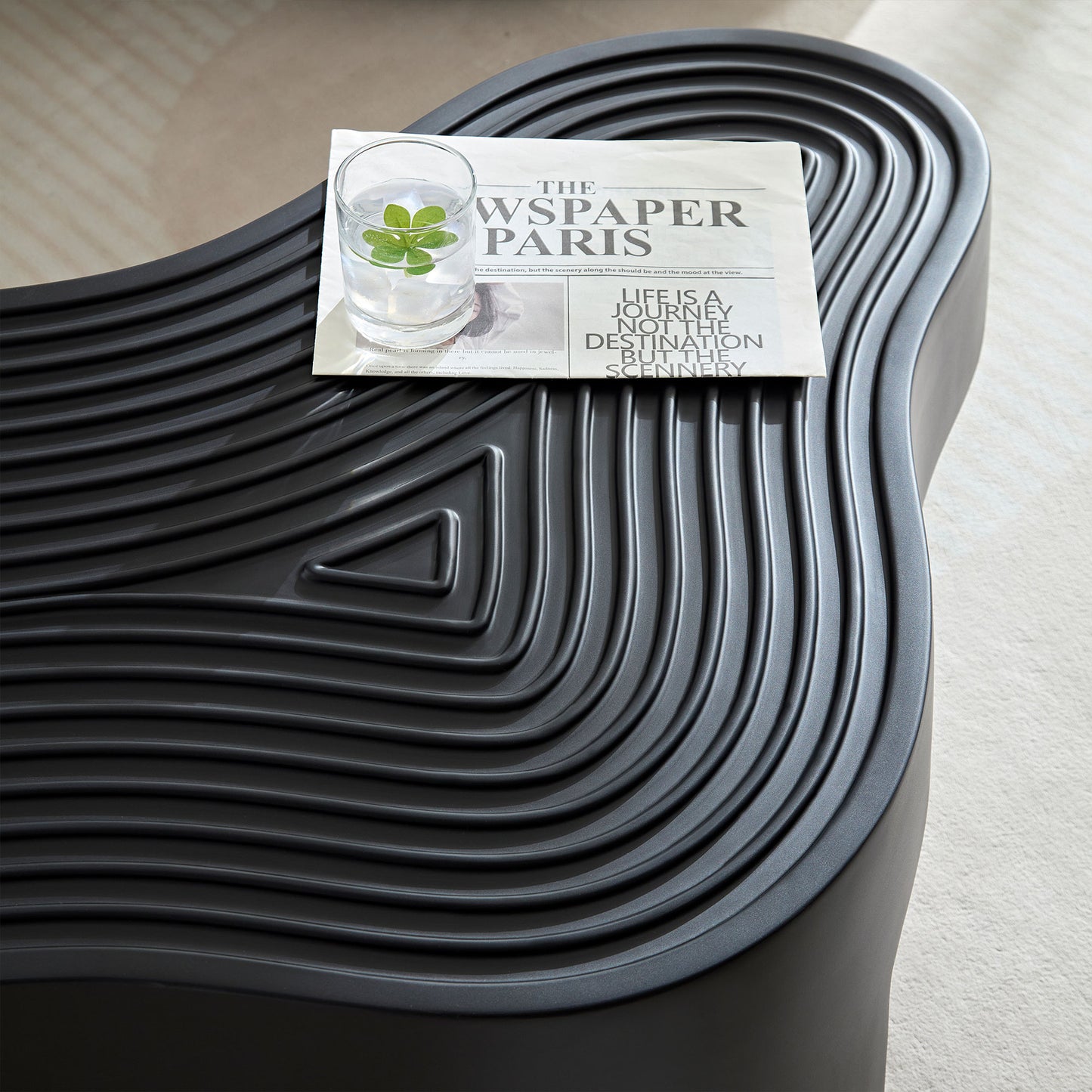 Black textured outdoor bench with glass and newspaper on top