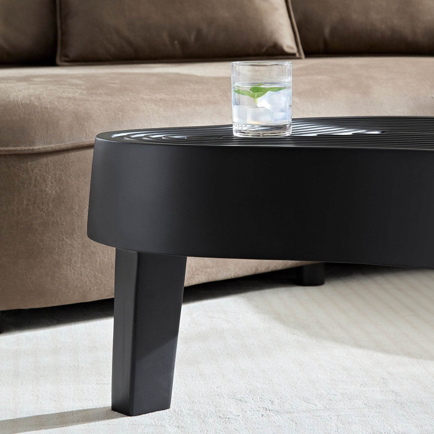 Modern black coffee table with ribbed top surface and sleek tapered legs