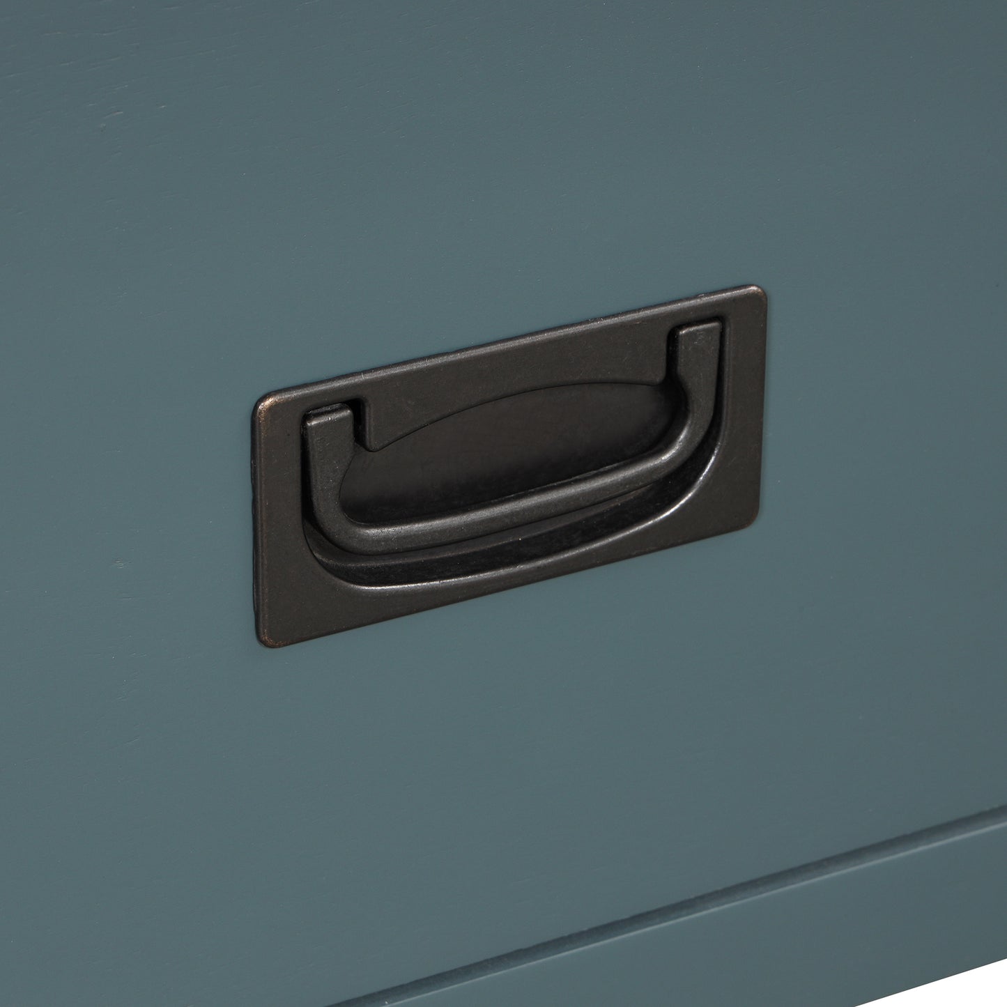 Closeup of a brushed bronze pull handle on a teal painted dresser drawer