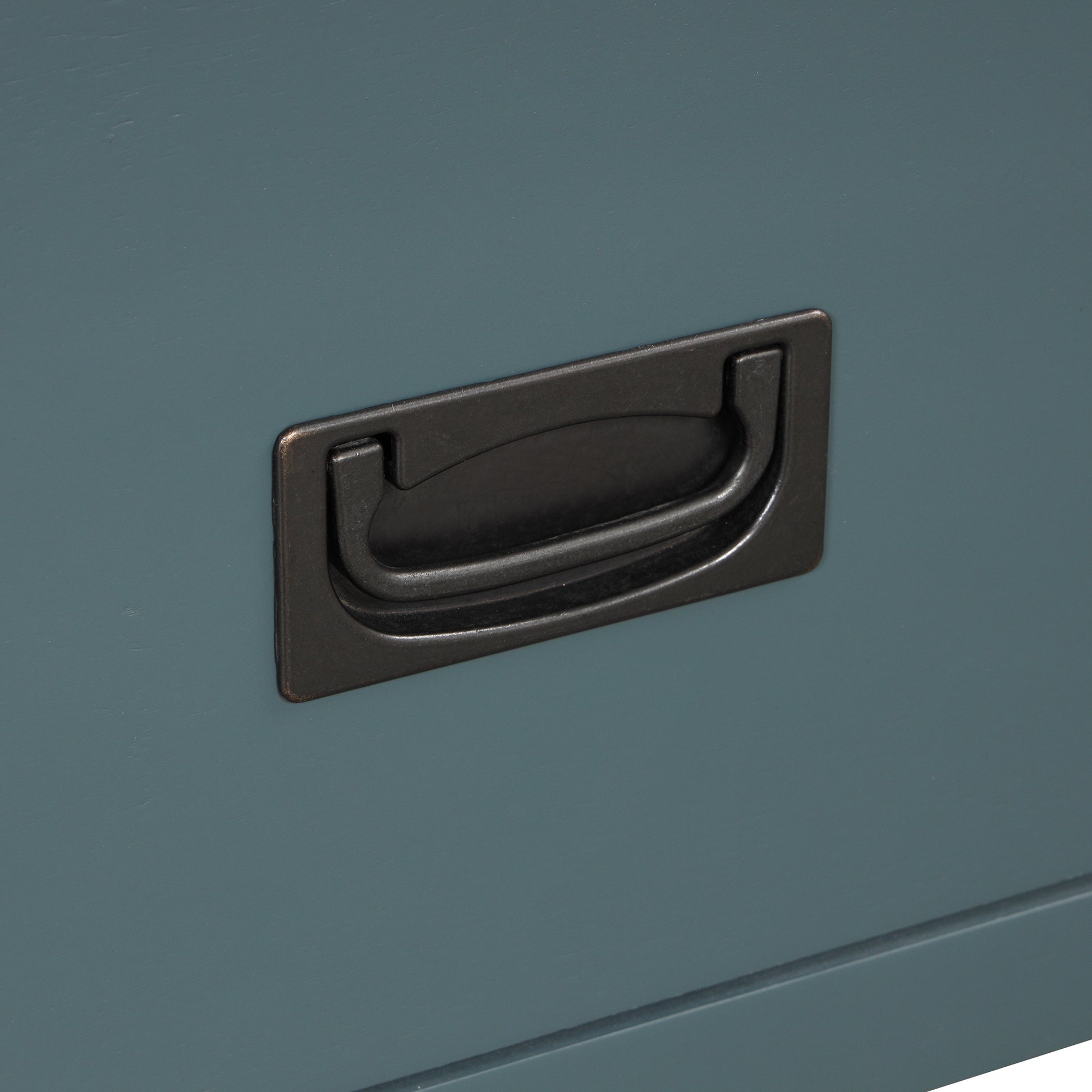 Closeup of a brushed bronze pull handle on a teal painted dresser drawer