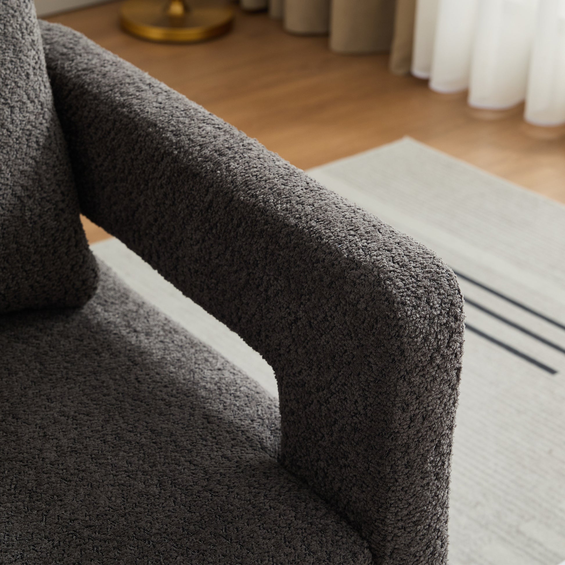 Dark grey textured boucle fabric armchair armrest and seat detail
