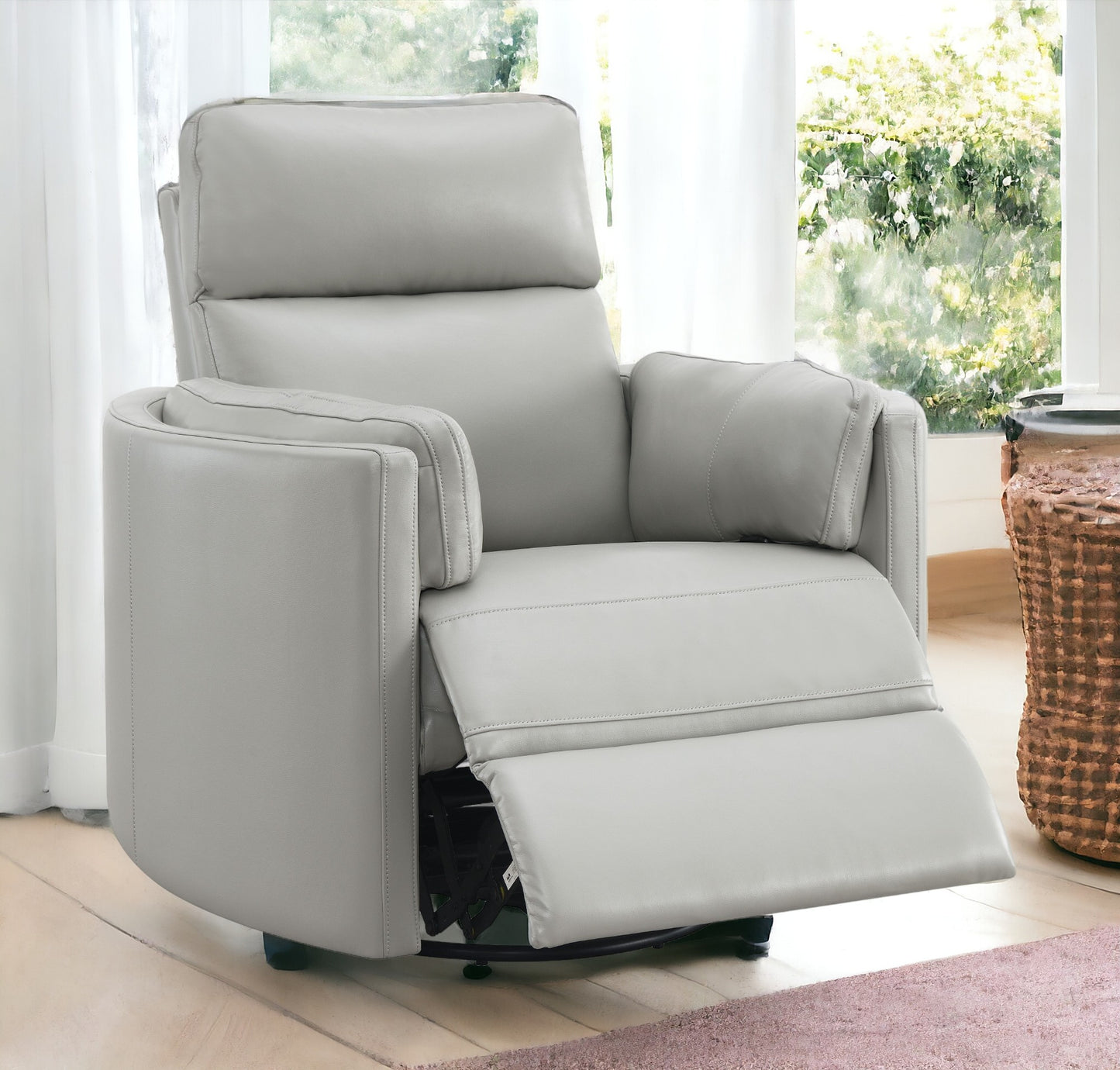 Light gray leather swivel recliner chair with plush cushioning and reclining footrest