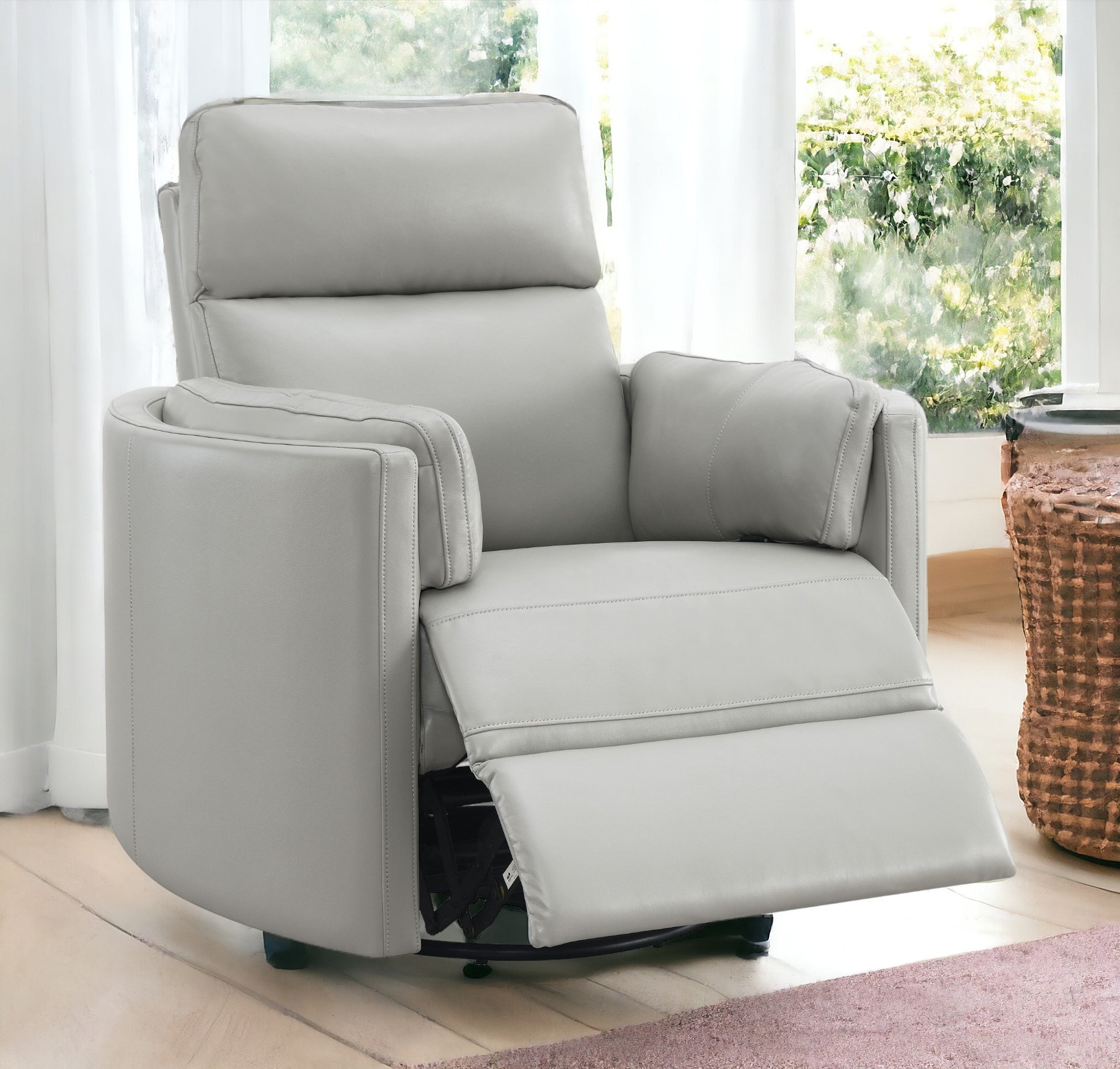 Light gray leather swivel recliner chair with plush cushioning and reclining footrest