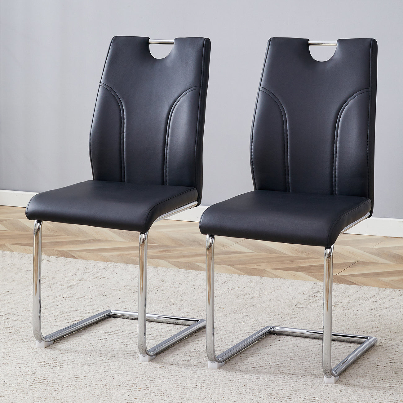 Two black faux leather dining chairs with chrome sled bases