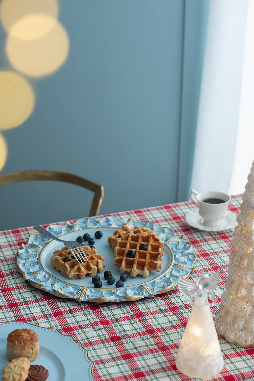 Blue ornate plate with golden trim holding two blueberry waffles and a fork