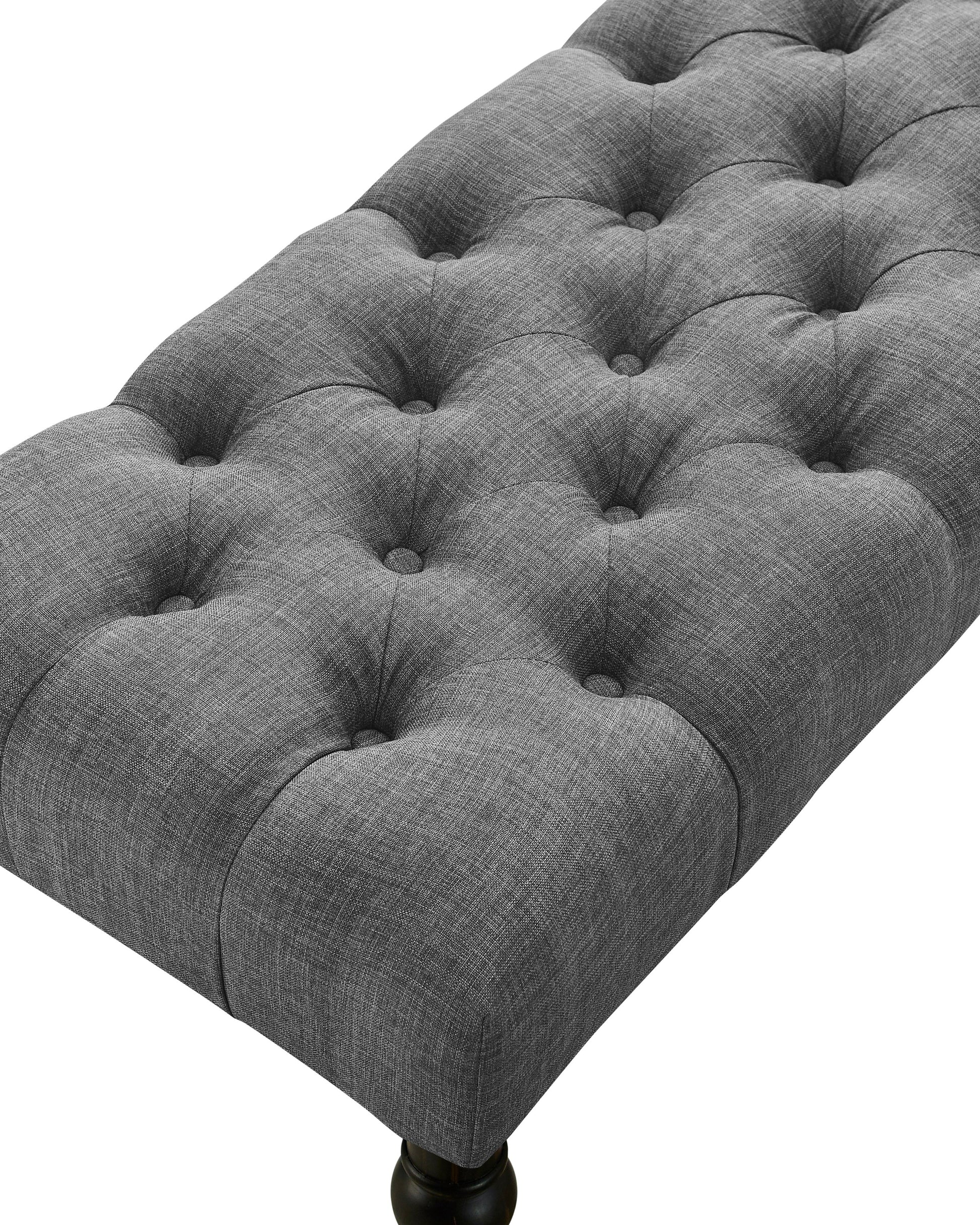 Closeup of a grey tufted upholstered bench