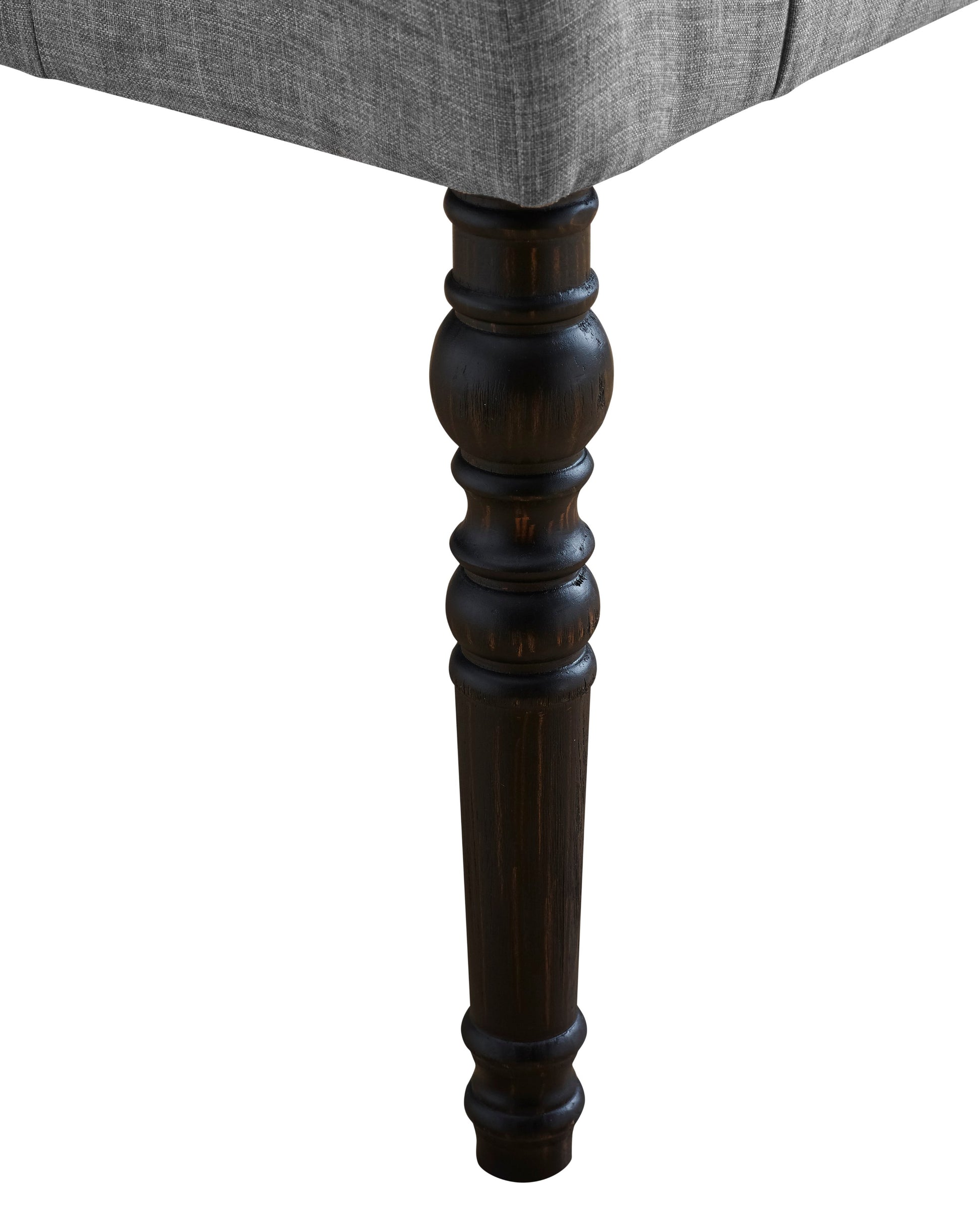 Gray upholstered furniture leg with dark wood carved foot