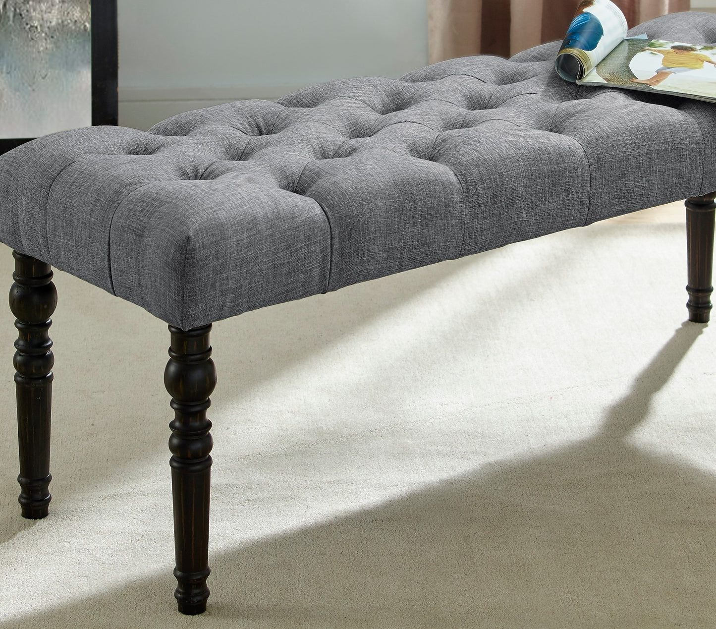 Grey fabric tufted bench with dark wood turned legs