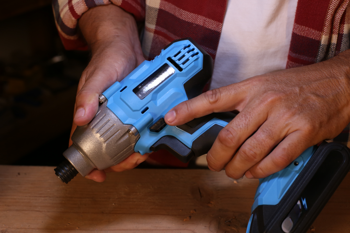 Closeup of hands holding a blue and silver cordless impact driver for DIY tasks
