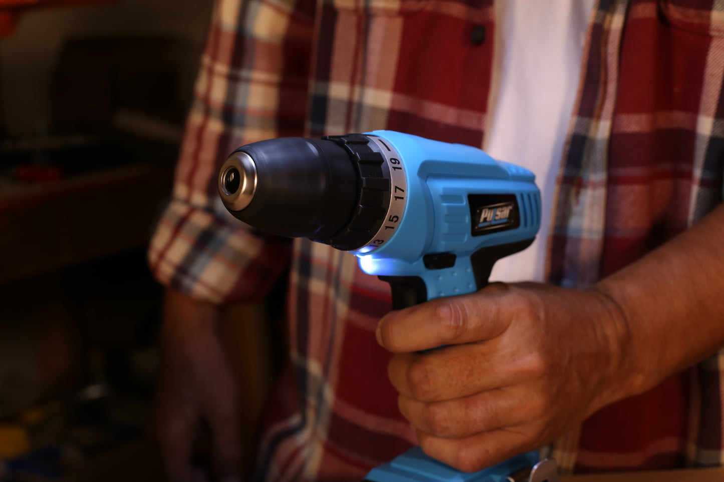 Close up of a blue Pulsar cordless drill with a metal chuck held by a hand