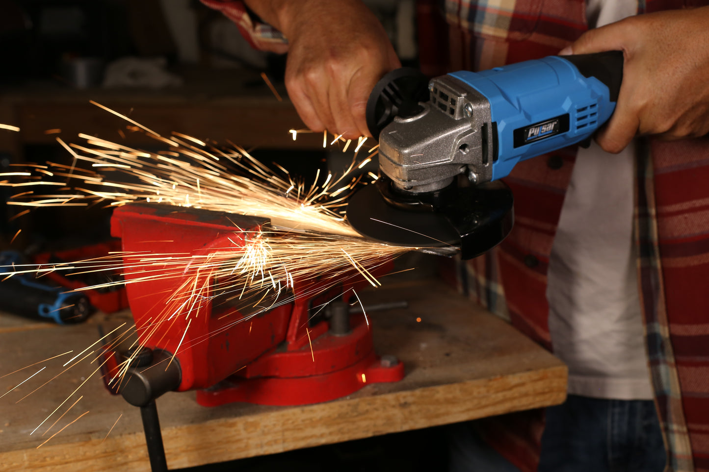 Blue Pulsar angle grinder sparks while cutting metal held in a red vise