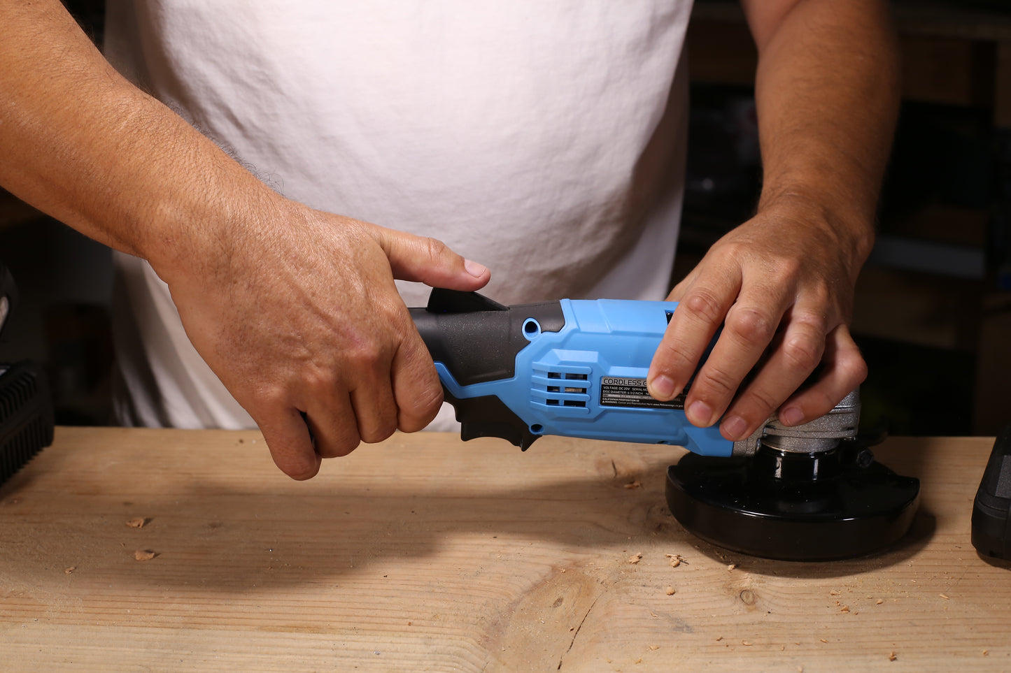 Blue V cordless angle grinder with black grip held by a person