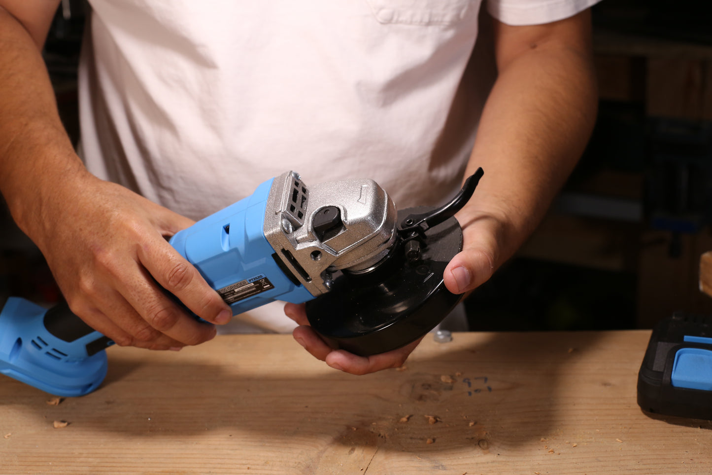 Blue and silver cordless angle grinder held by hands for assembly or use