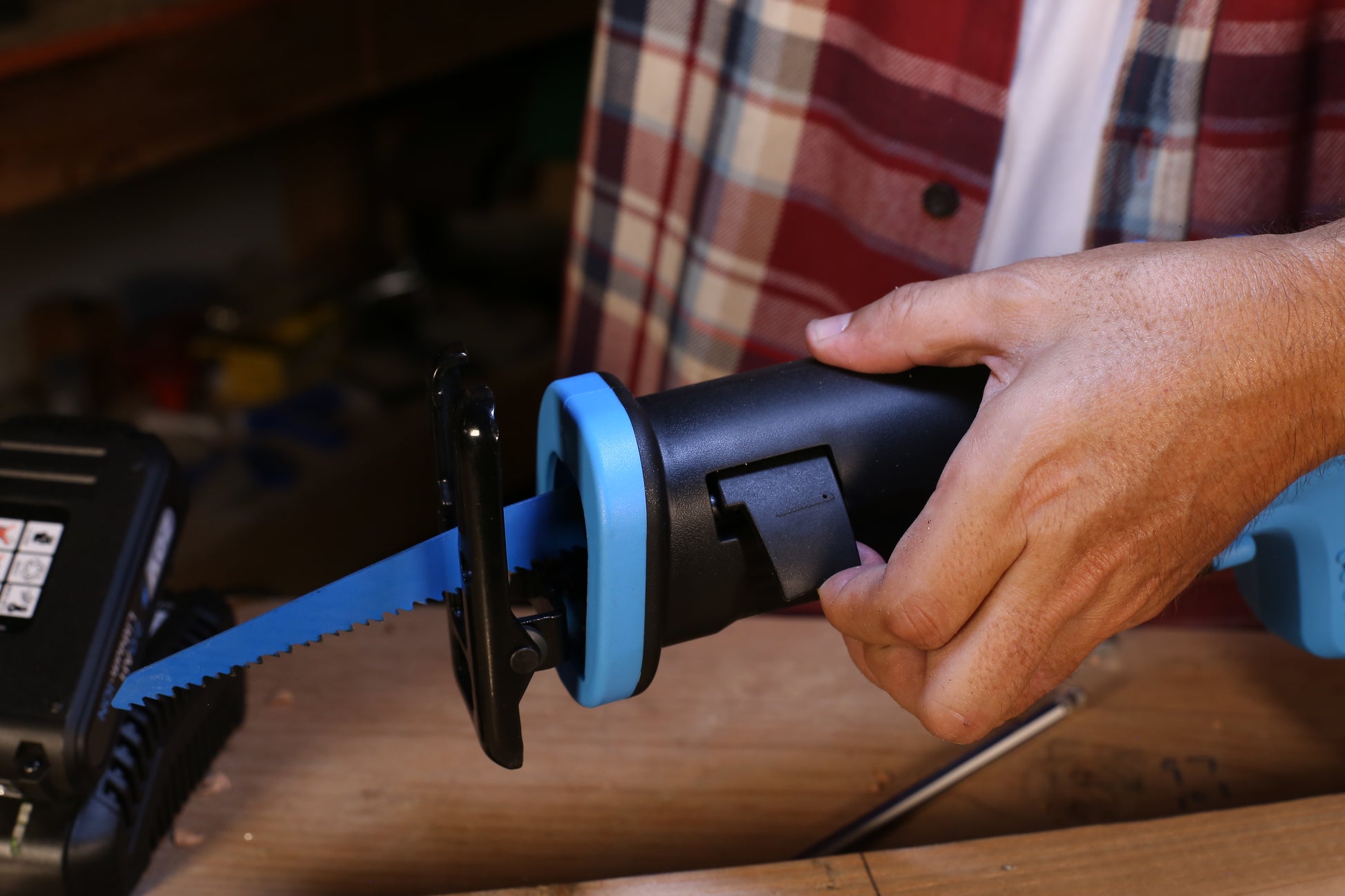 Black and blue reciprocating saw with sharp blue blade held by a hand