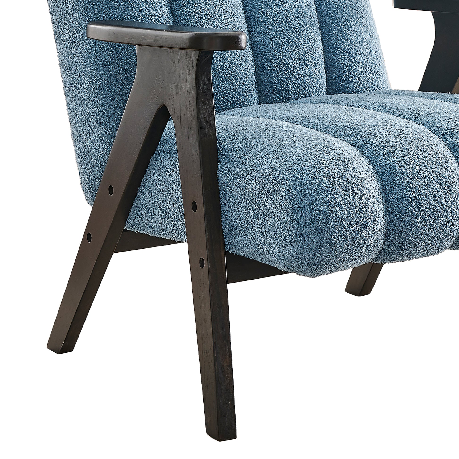 Closeup of a plush blue boucle armchair with dark wood legs showcasing its textured upholstery