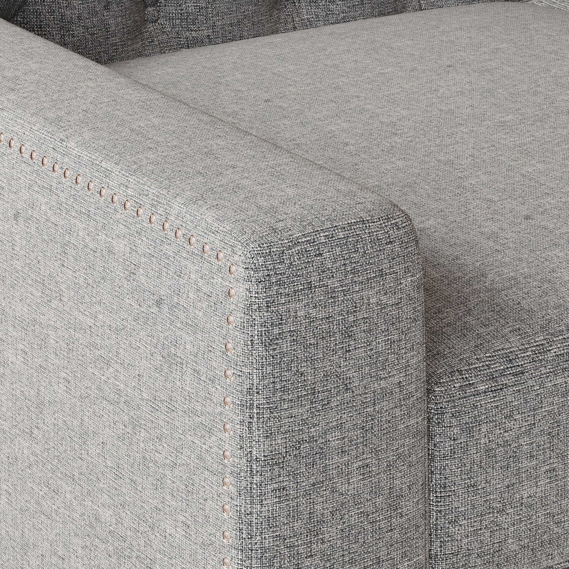 Closeup of grey textured fabric sofa arm with decorative nailhead trim detail