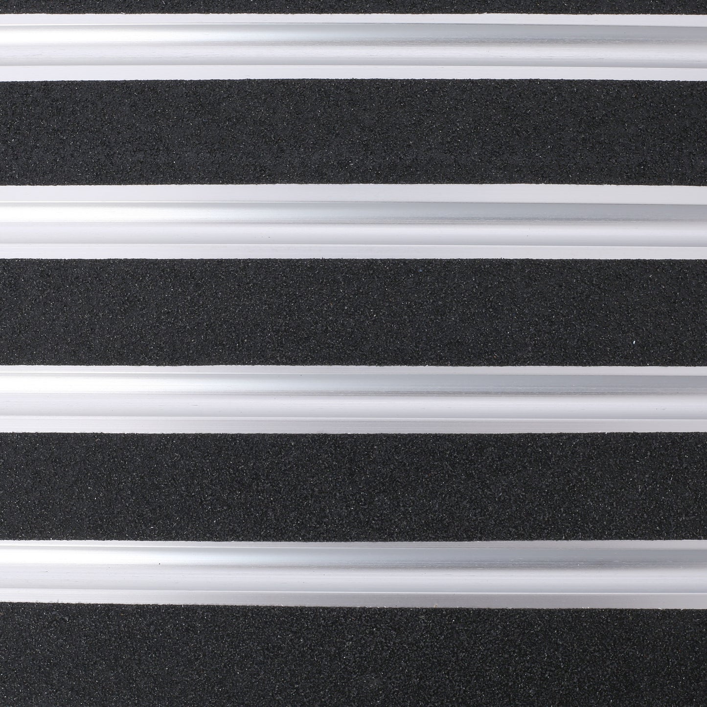 Closeup of black rubberized grip tape with silver aluminum strips ideal for nonslip stair treads