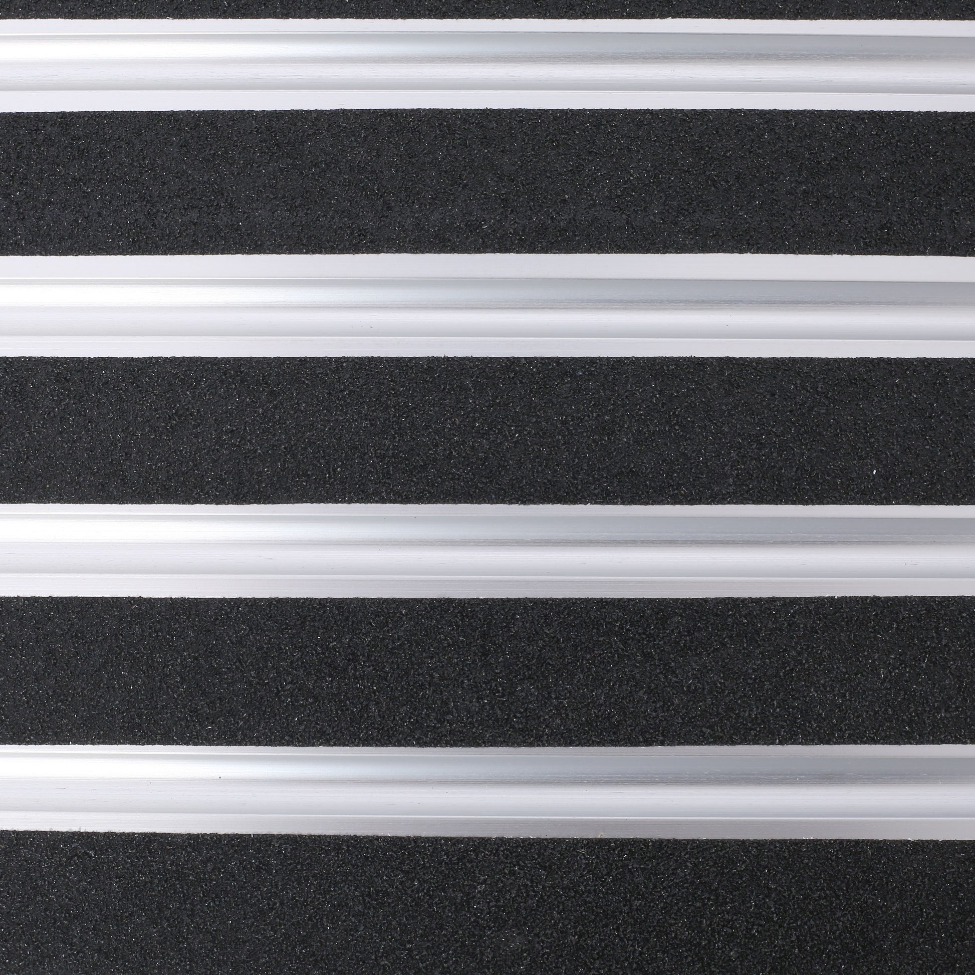 Closeup of black rubberized grip tape with silver aluminum strips ideal for nonslip stair treads