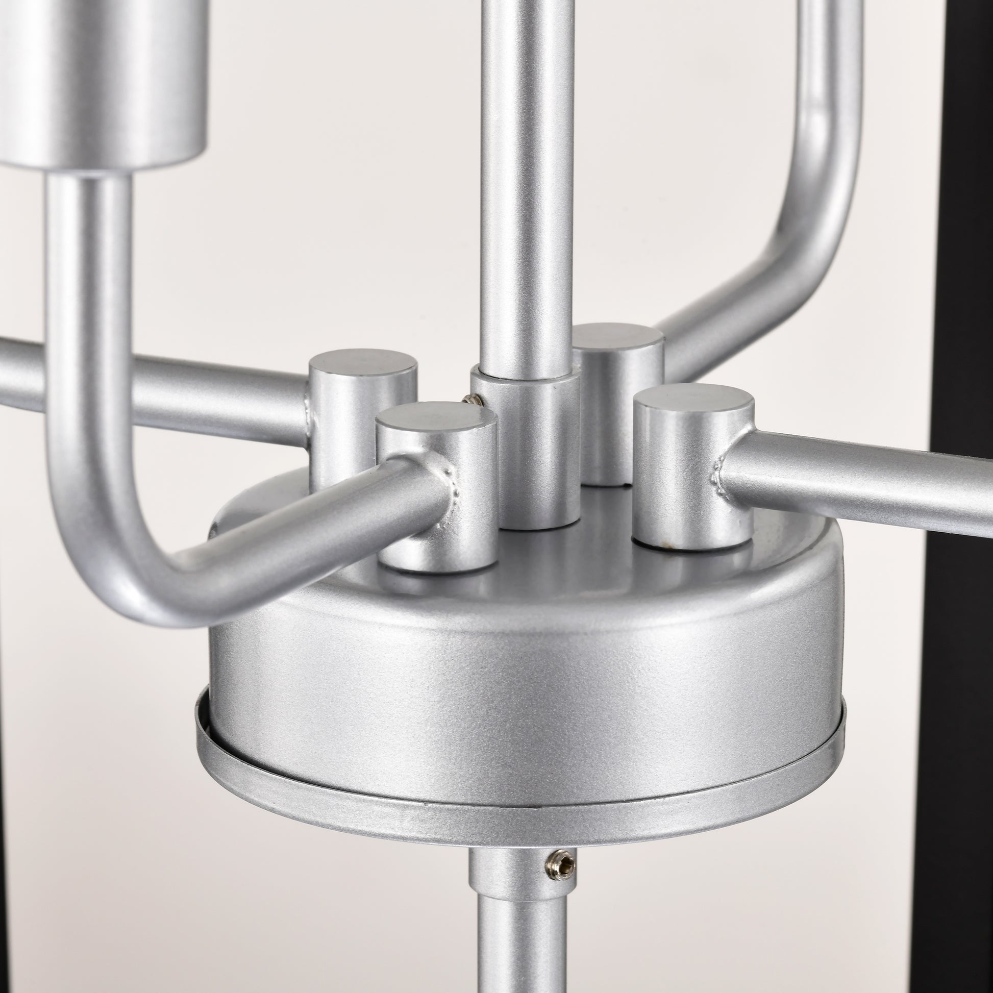 Closeup of brushed silver chandelier base with curved arms and cylinder accents