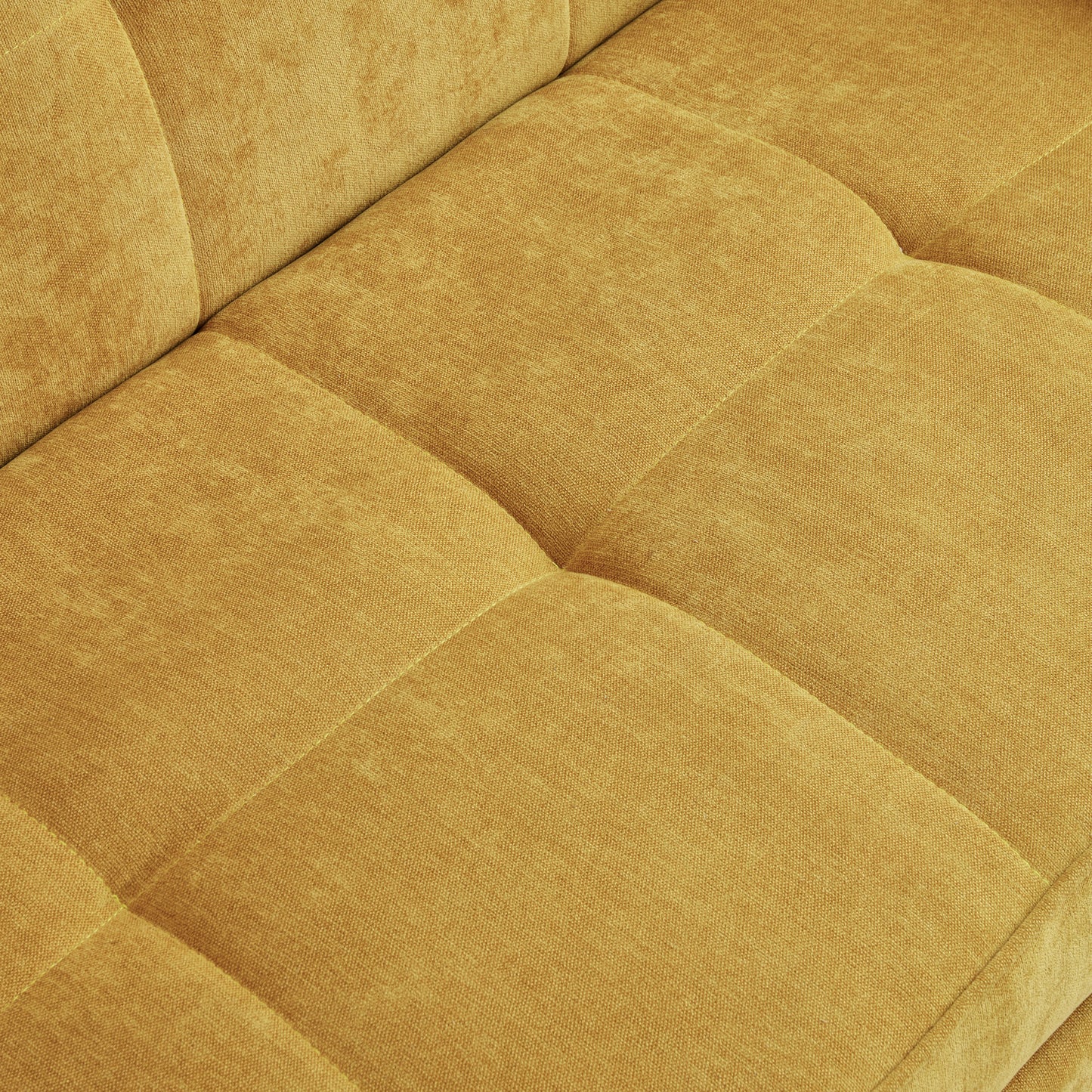 Closeup of textured mustard yellow chenille fabric on a tufted sofa cushion