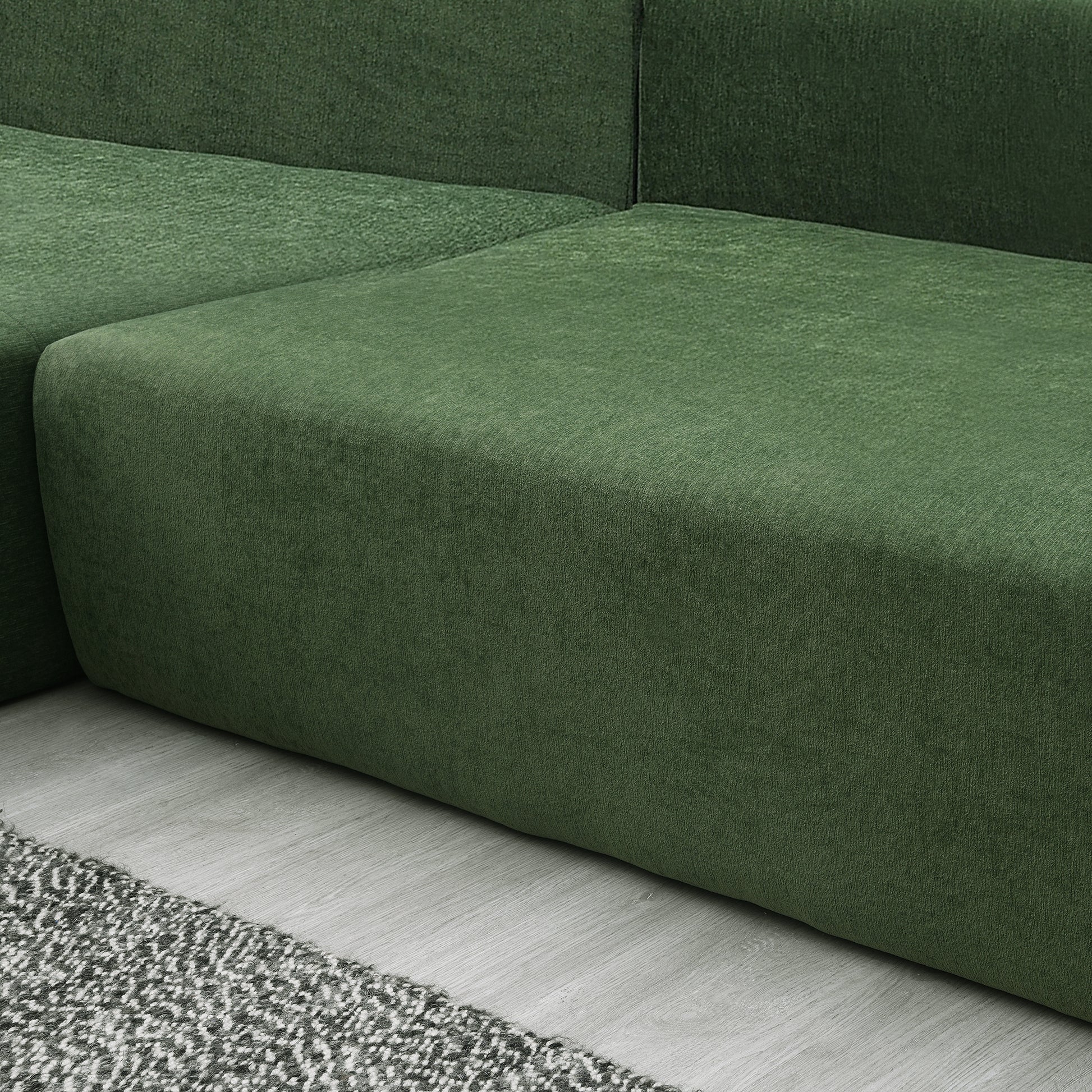 Deep green velvet sectional sofa corner with plush texture