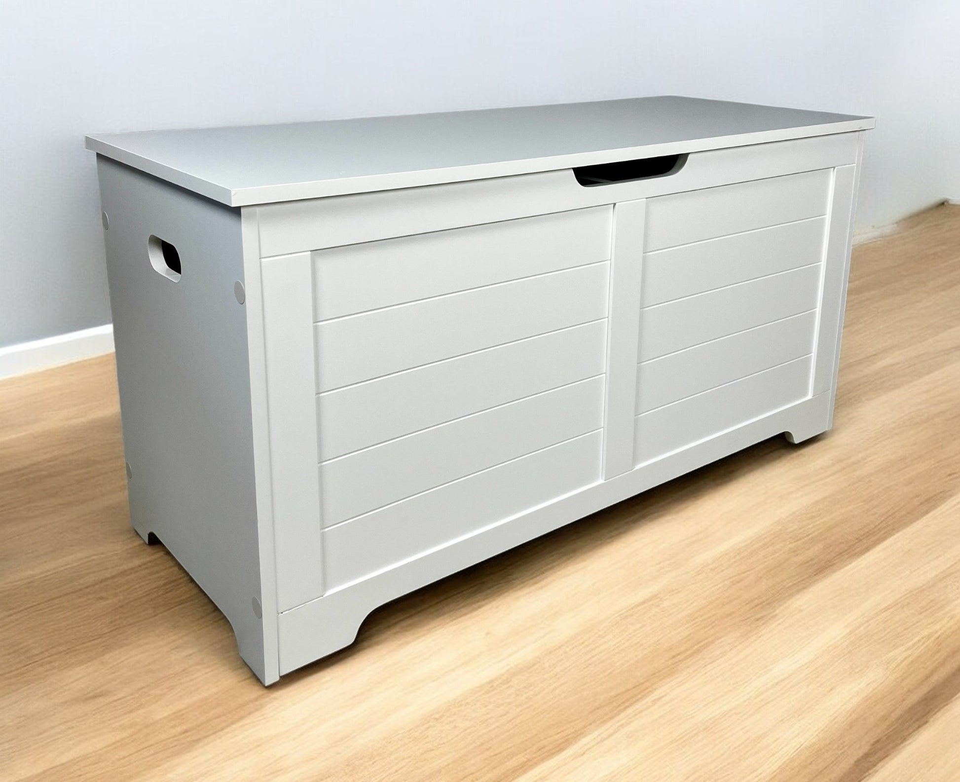 Grey wooden toy chest with horizontal paneling and cutout handles