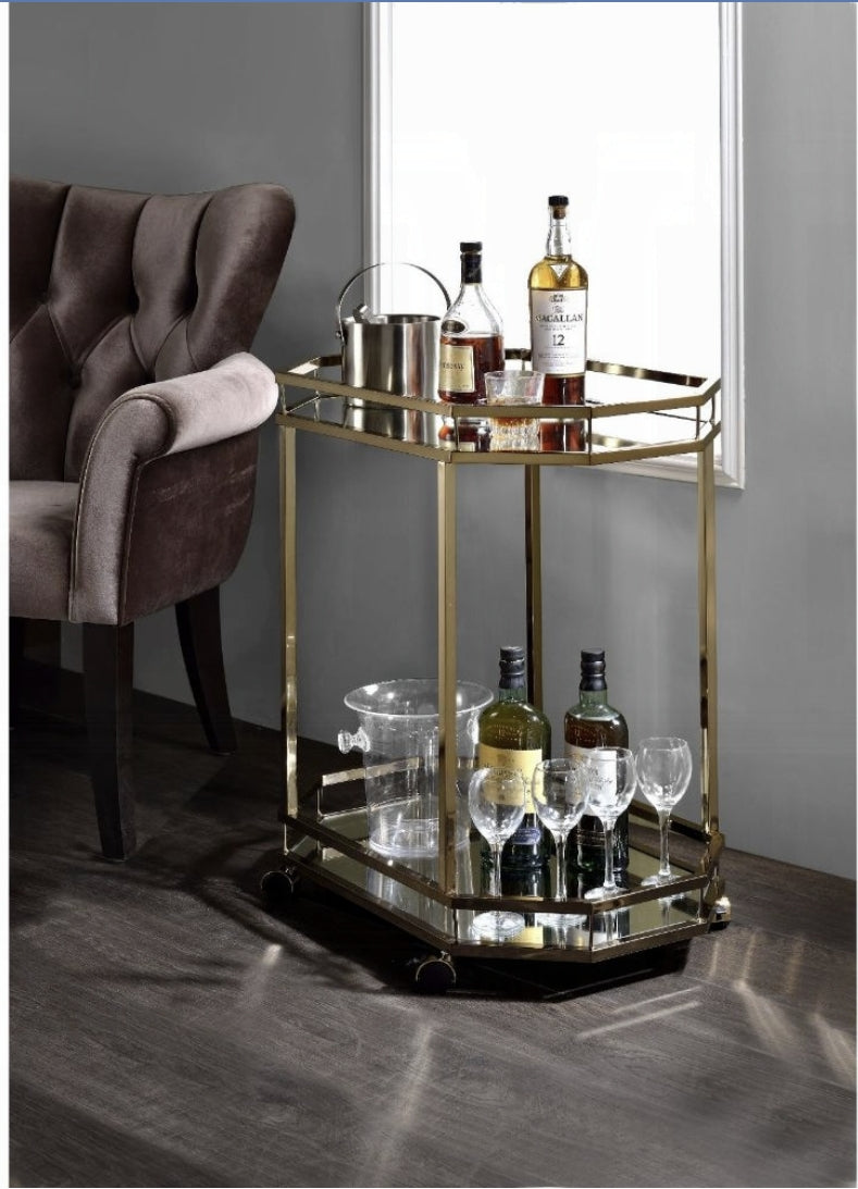 Antique gold bar cart with mirrored shelves holding liquor bottles and glassware