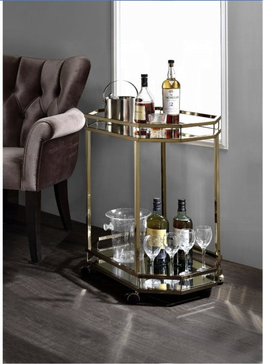 Antique gold bar cart with mirrored shelves holding liquor bottles and glassware