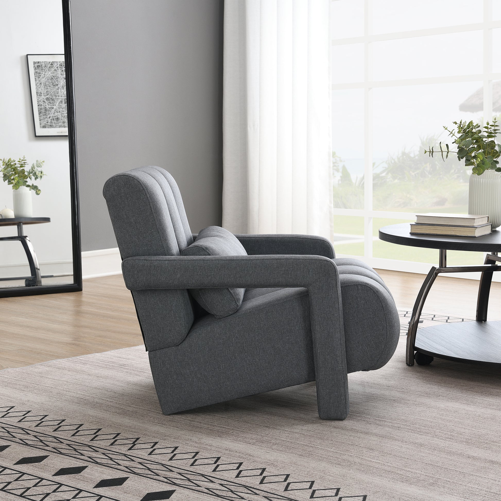 Dark grey upholstered armchair with channel stitching and a lumbar pillow
