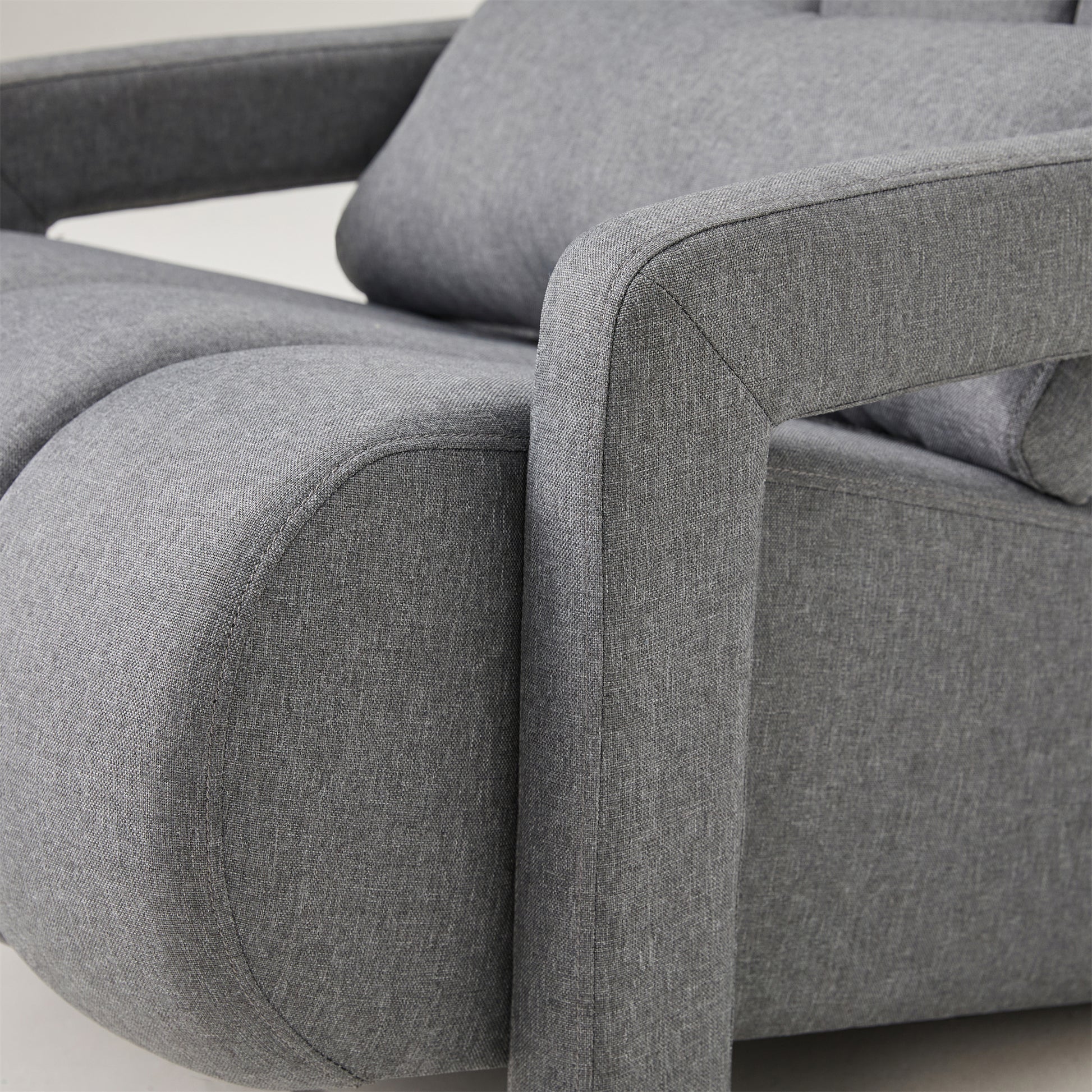 Closeup of a textured gray fabric armchair with curved arms and visible stitching detail