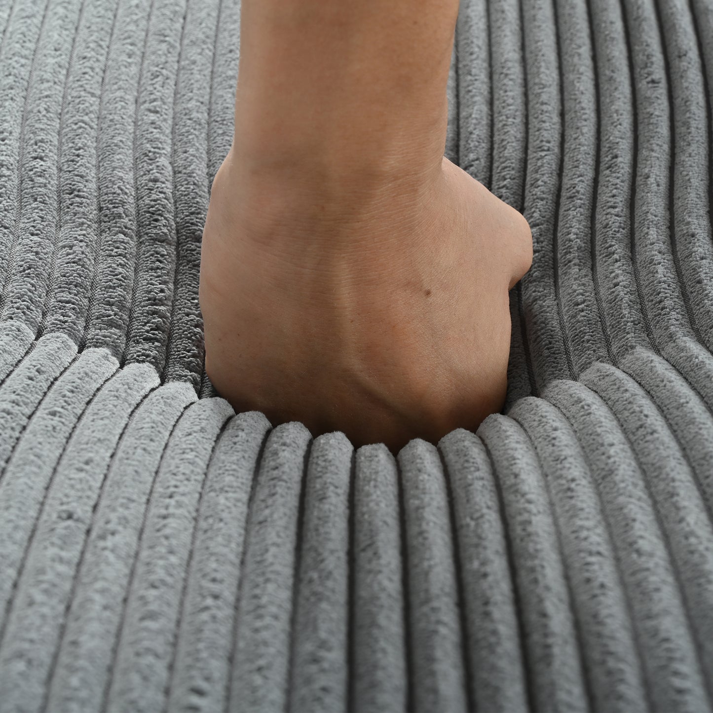 Hand pressing into soft grey corduroy fabric highlighting plush comfort