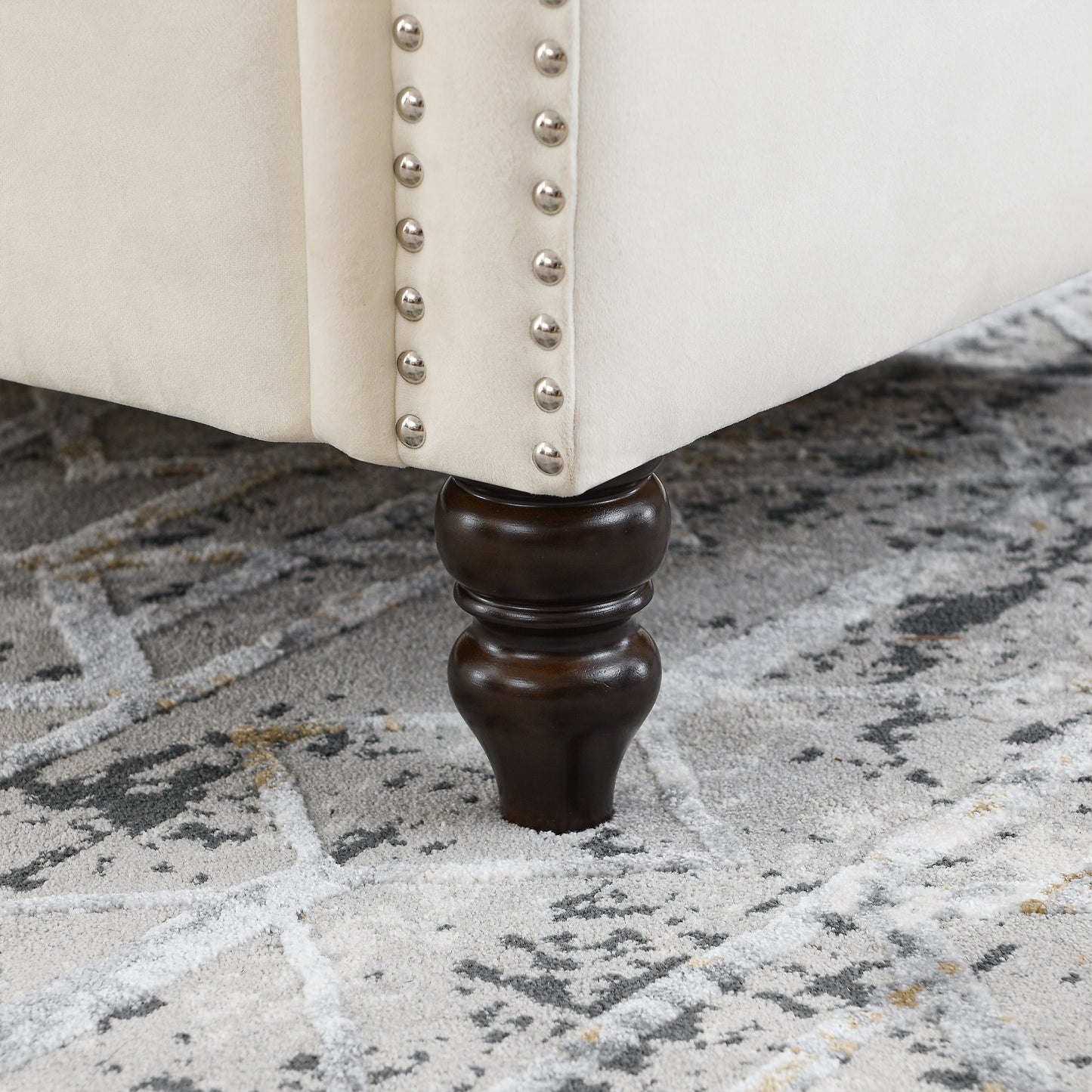 Cream velvet ottoman with silver nailhead trim and dark wood leg