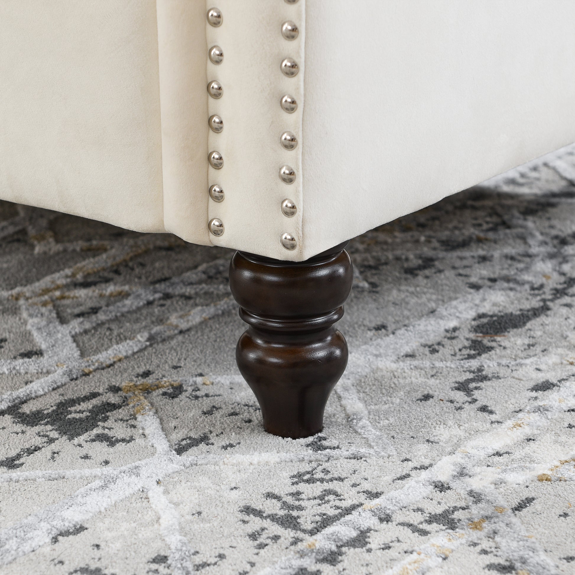 Cream velvet ottoman with silver nailhead trim and dark wood leg