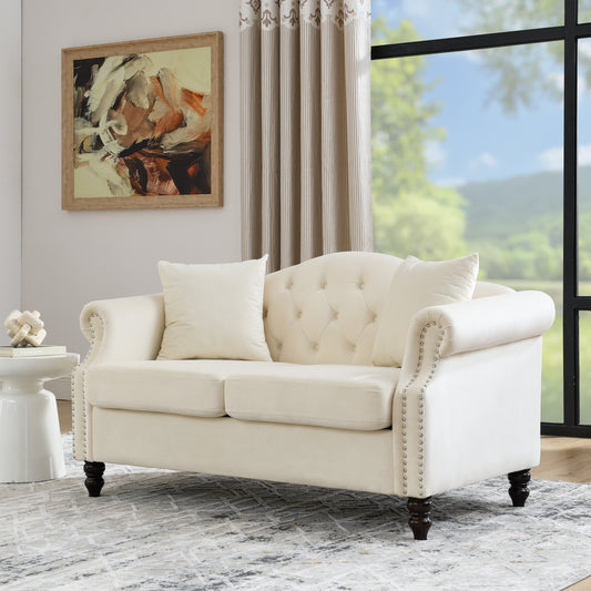 Cream velvet tufted sofa with silver nailhead trim and rolled arms on dark wood legs
