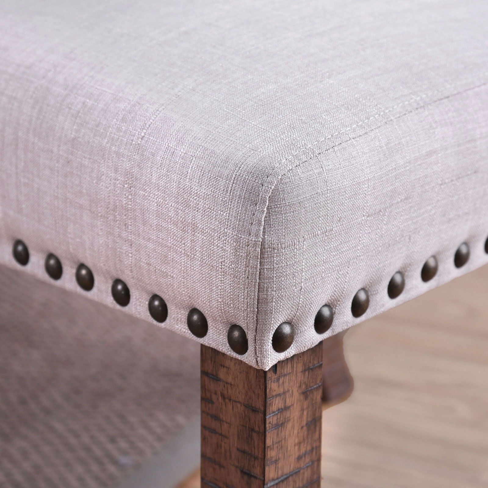 Neutral linen upholstered ottoman corner with decorative nailhead trim