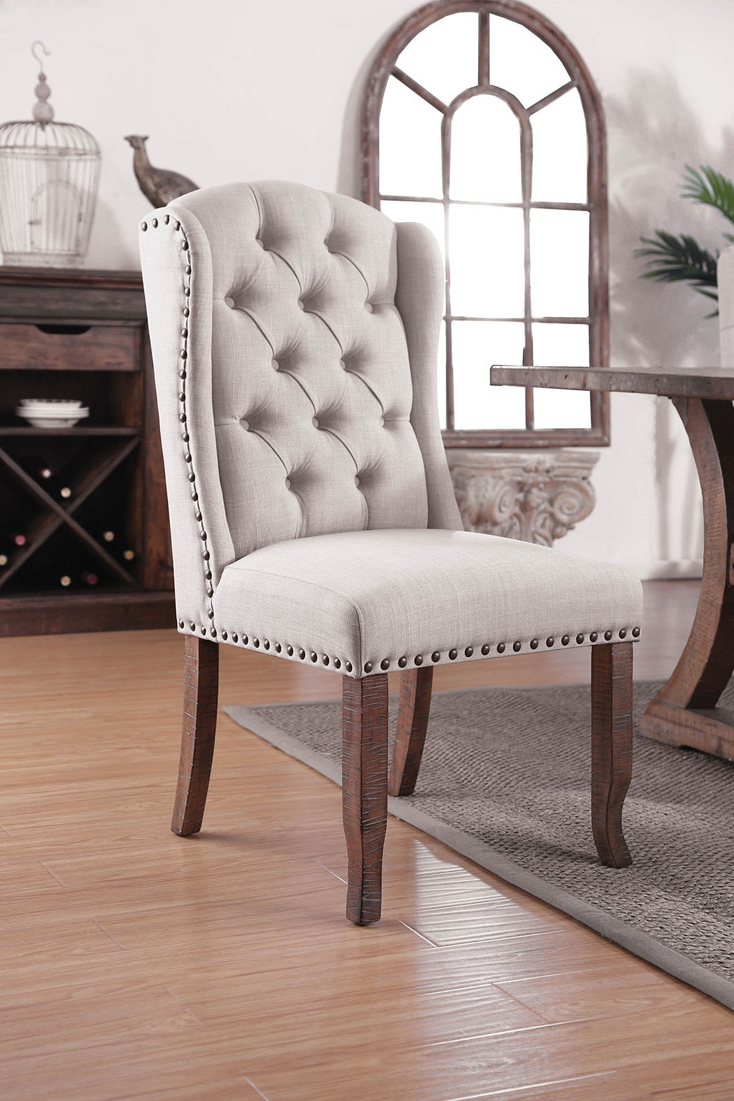 Light gray upholstered dining chair with tufted back and nailhead trim
