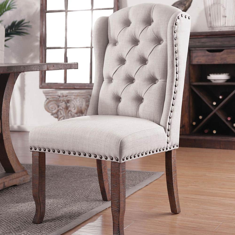Light gray tufted wingback dining chair with nailhead trim and dark wood legs