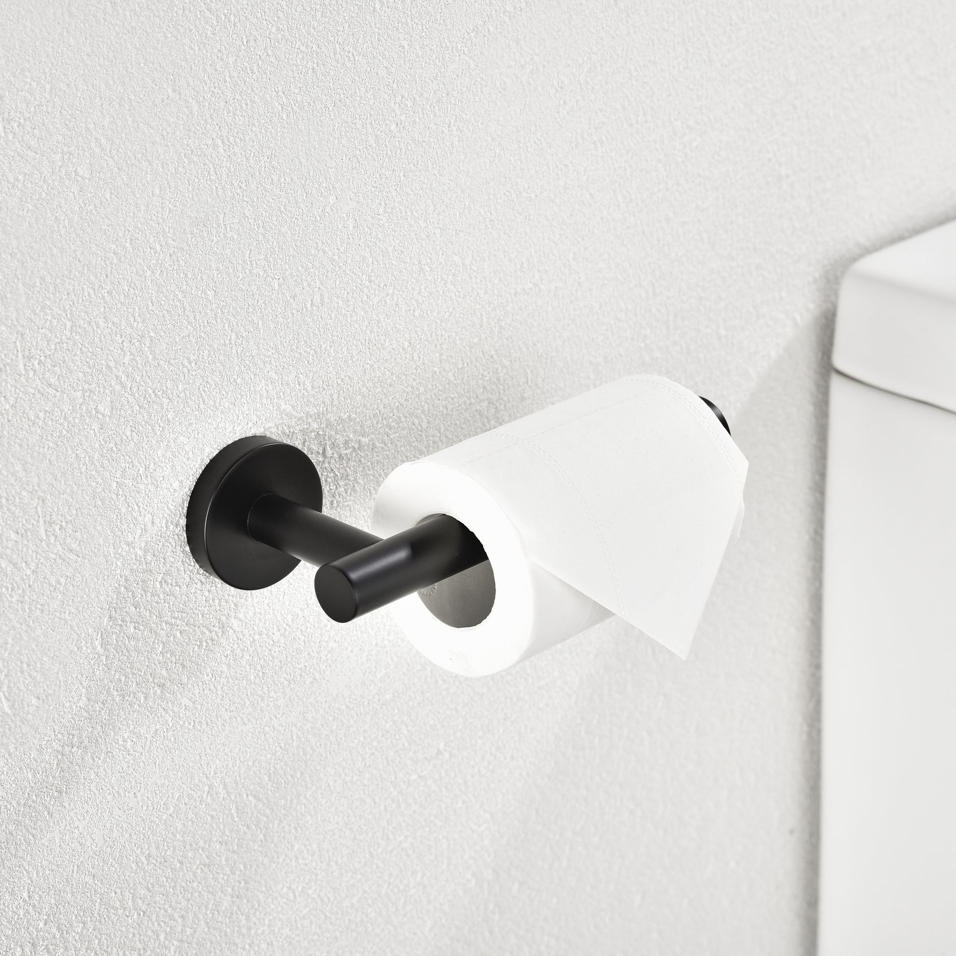 Modern matte black toilet paper holder with single roll dispenser mounted on a textured white wall