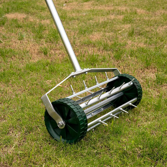 Garden lawn aerator with metal spikes and green wheels on grass