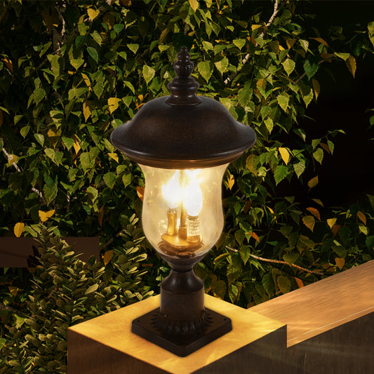Traditional bronze outdoor post light with clear seeded glass and ornate finial detail illuminating a patio setting