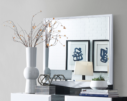 White ceramic vase with modern spherical base holding decorative branches with small amber buds
