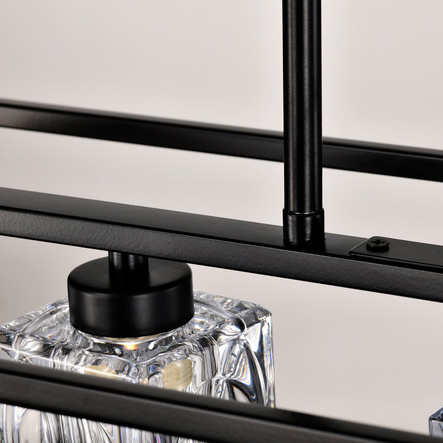 Closeup of black metal bar with textured surface and a clear faceted glass shade on a modern chandelier