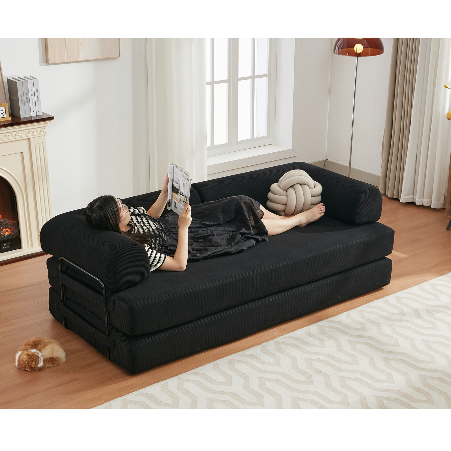 Black corduroy sofa bed with a person reading ideal for modern living spaces