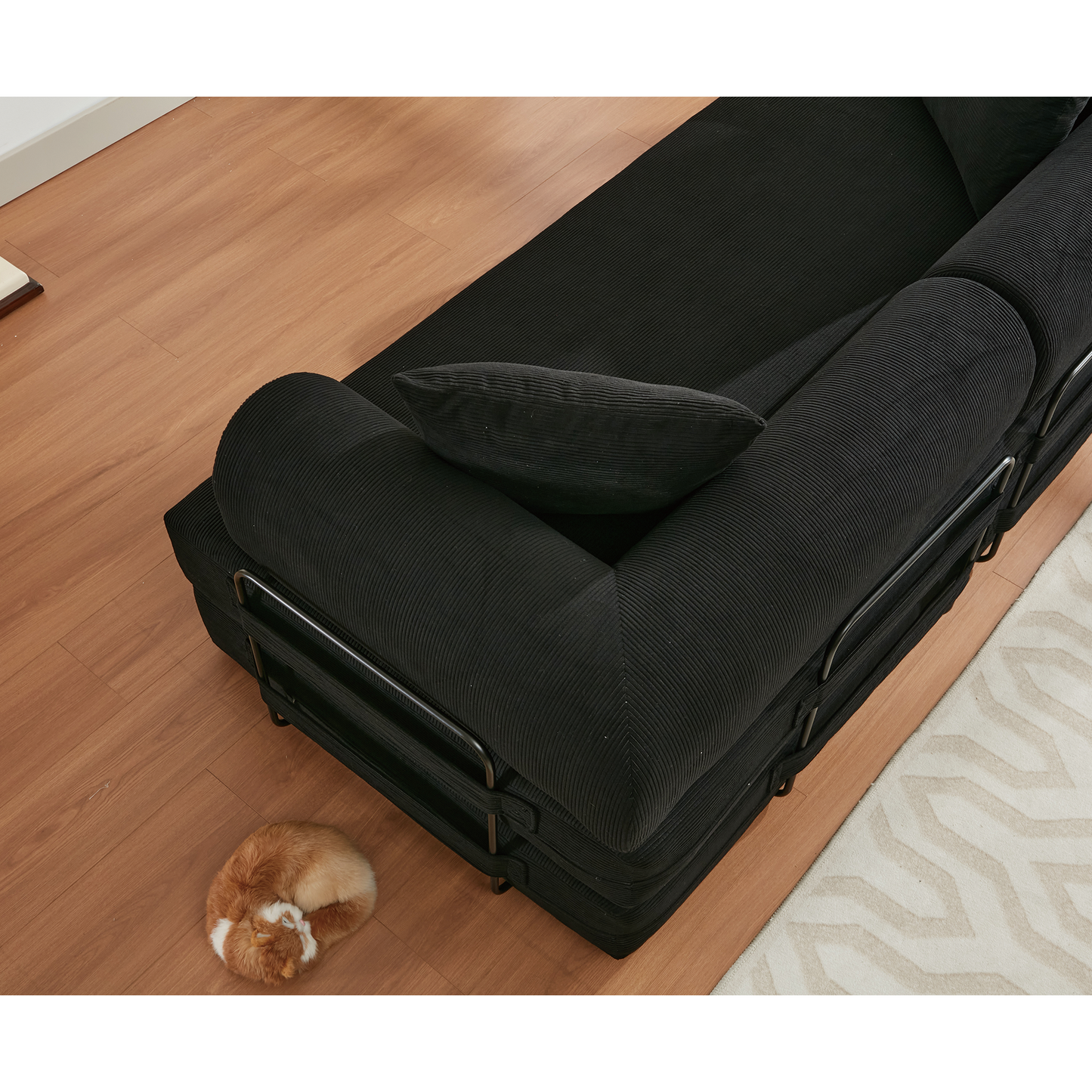 Black corduroy sectional sofa with metal frame and lumbar pillow on wood floor