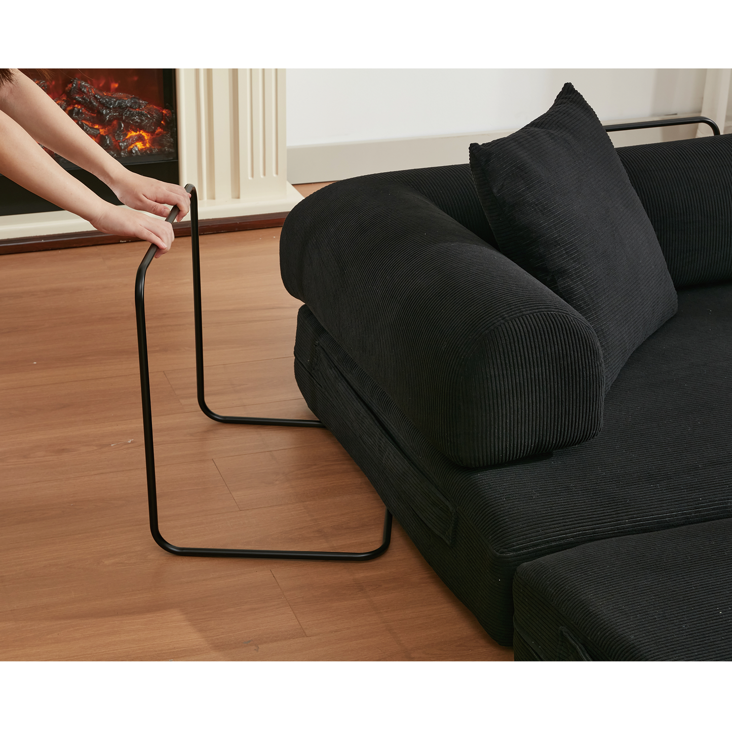 Black corduroy sectional sofa with a black metal Ctable attachment for easy laptop use