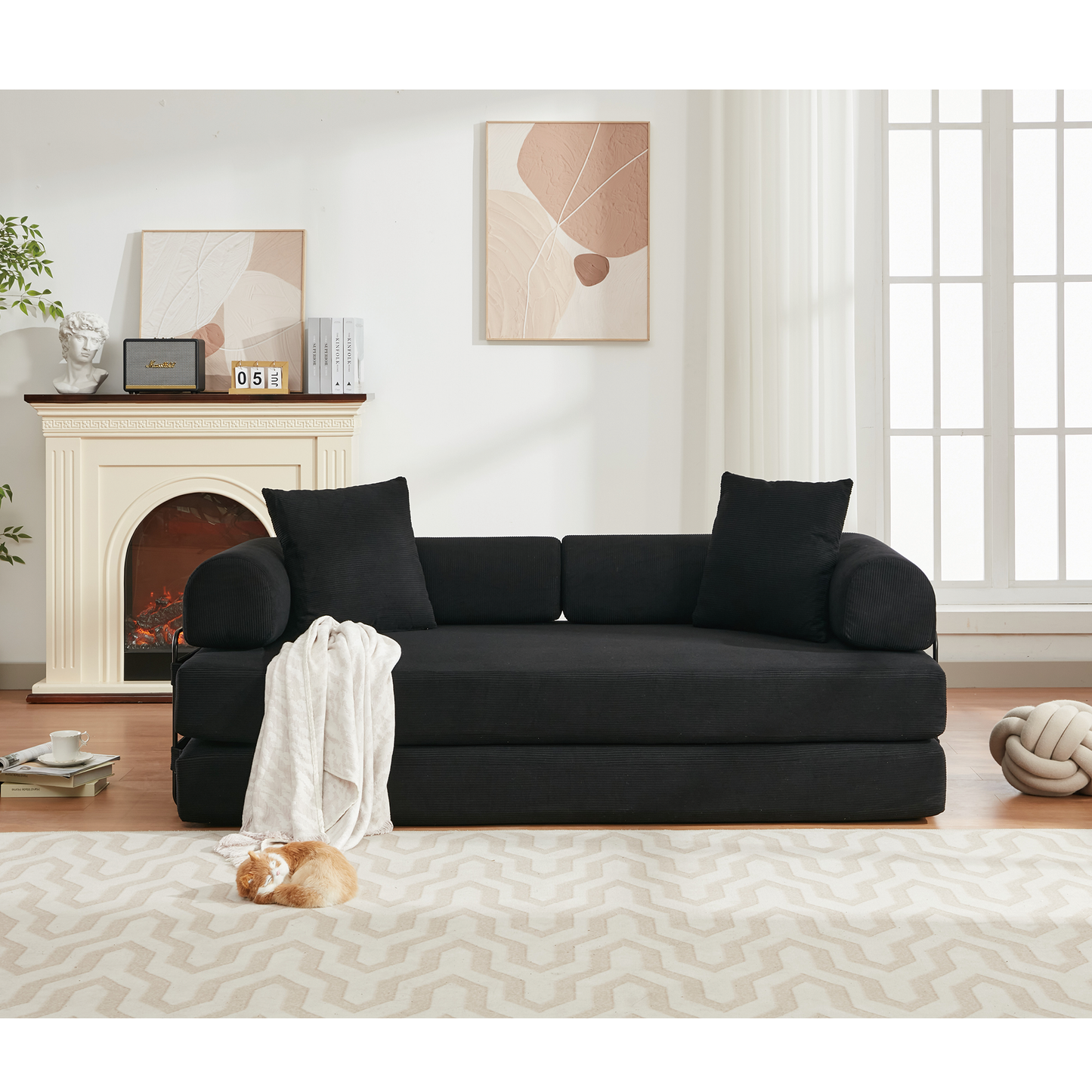 Plush black corduroy sofa with plush throw pillows and a white blanket draped over it