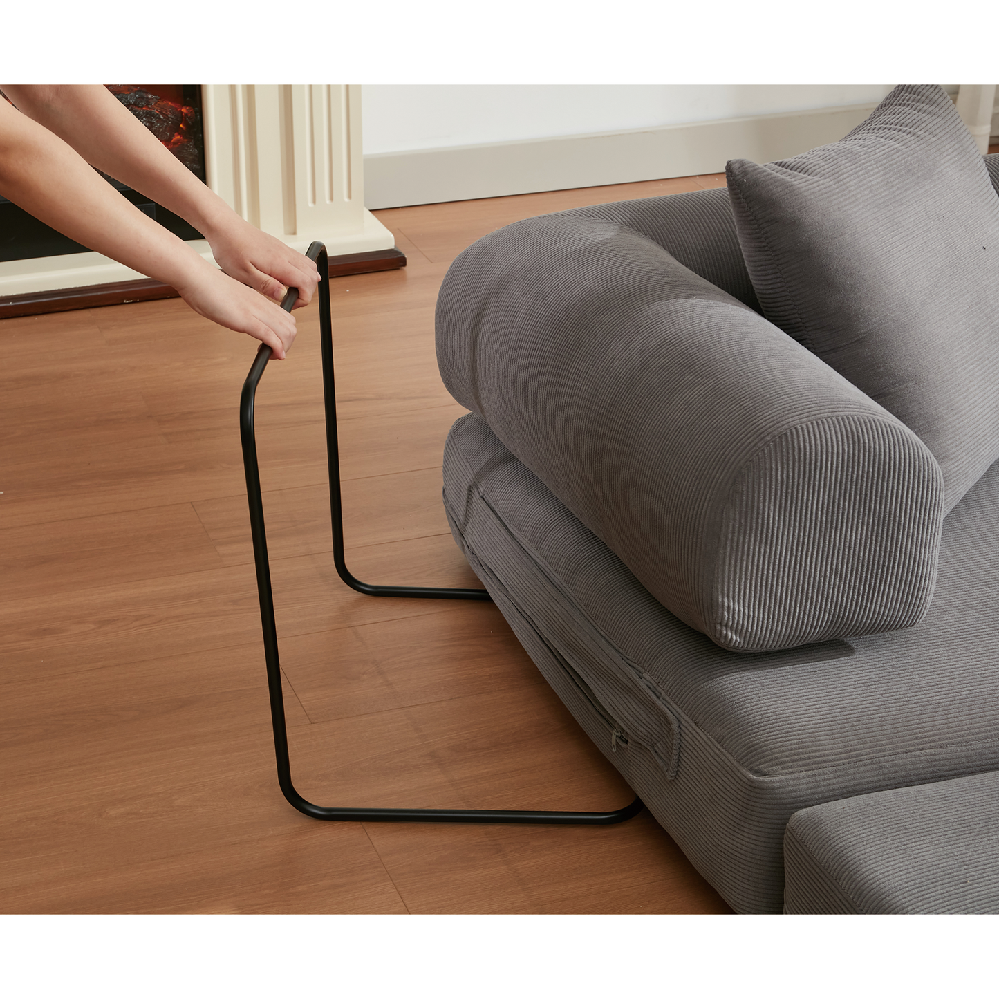 Closeup of hands attaching a black metal leg to a grey corduroy sofa