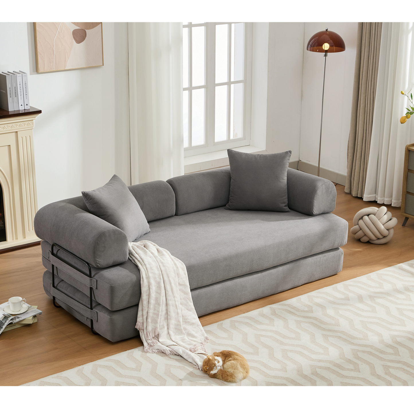 Gray corduroy sofa bed with plush pillows and a folded throw blanket
