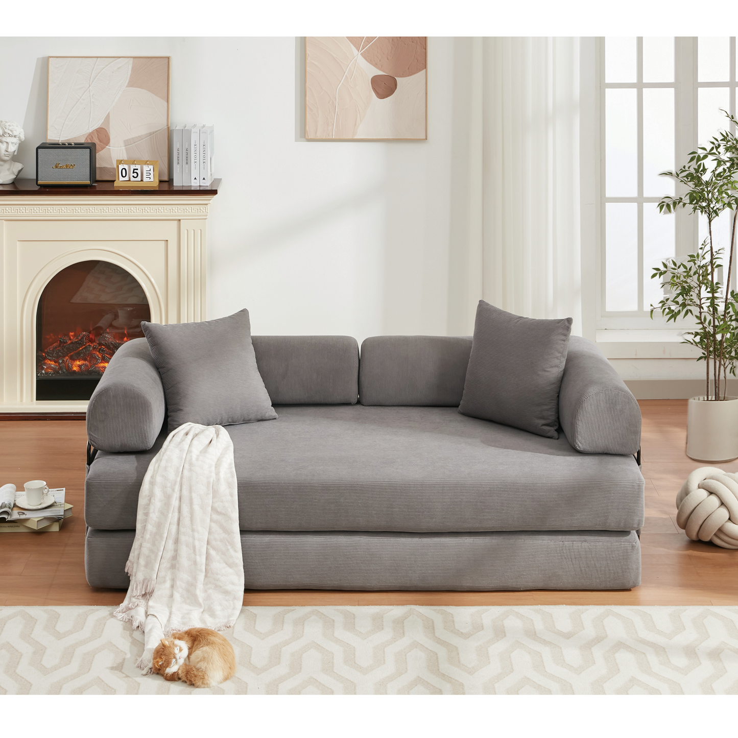 Gray corduroy sofa bed with two pillows and a draped blanket perfect for small living spaces