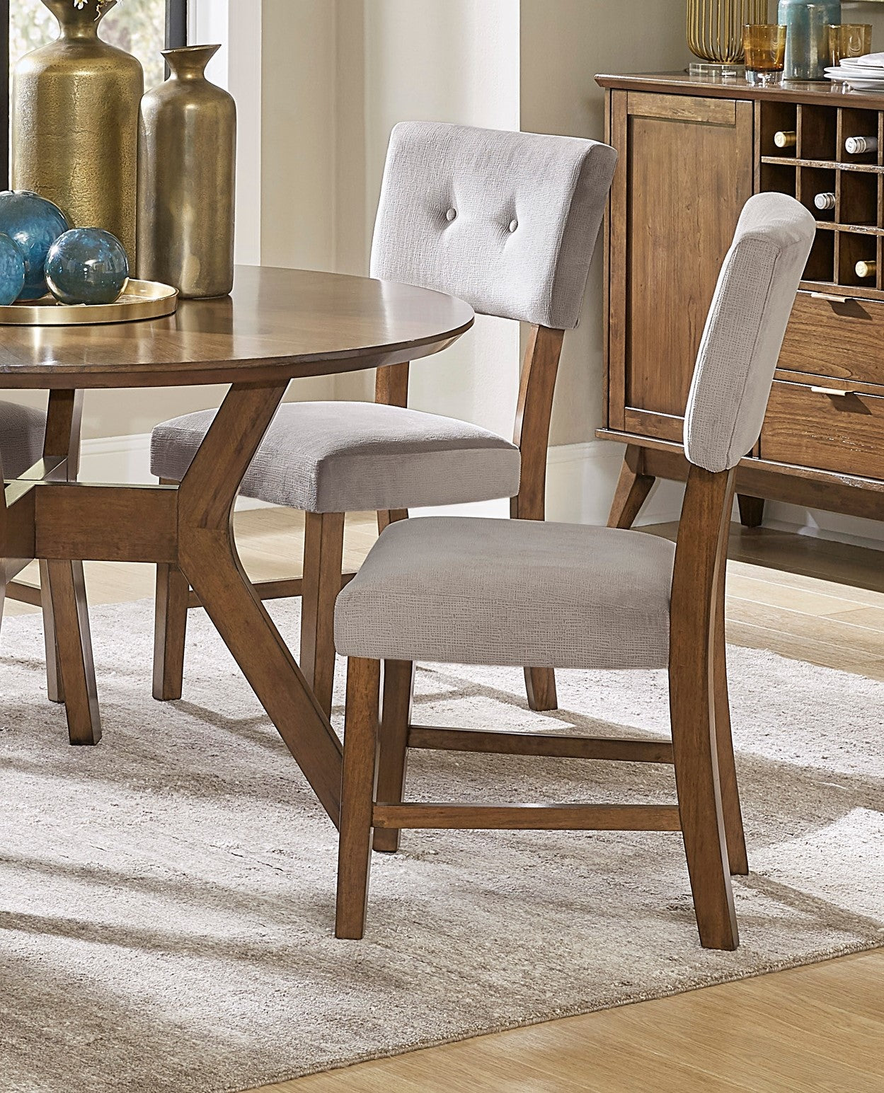Round wood dining table with upholstered grey chairs and wood accents